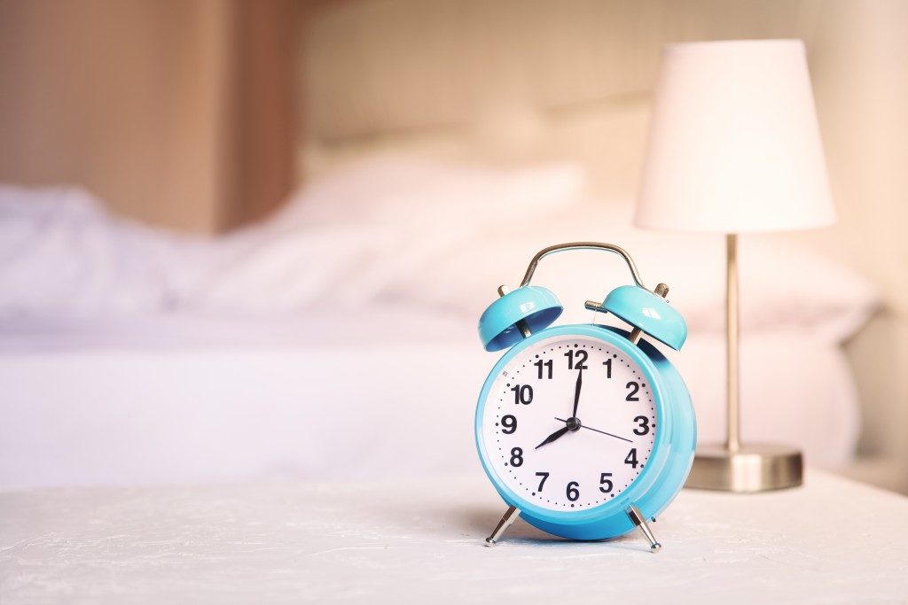blue alarm clock beside a bed