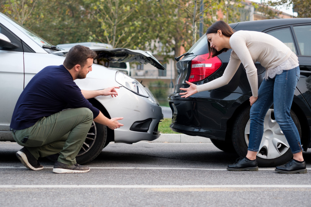 Male and female drivers calmly discussing the car accident on the road.